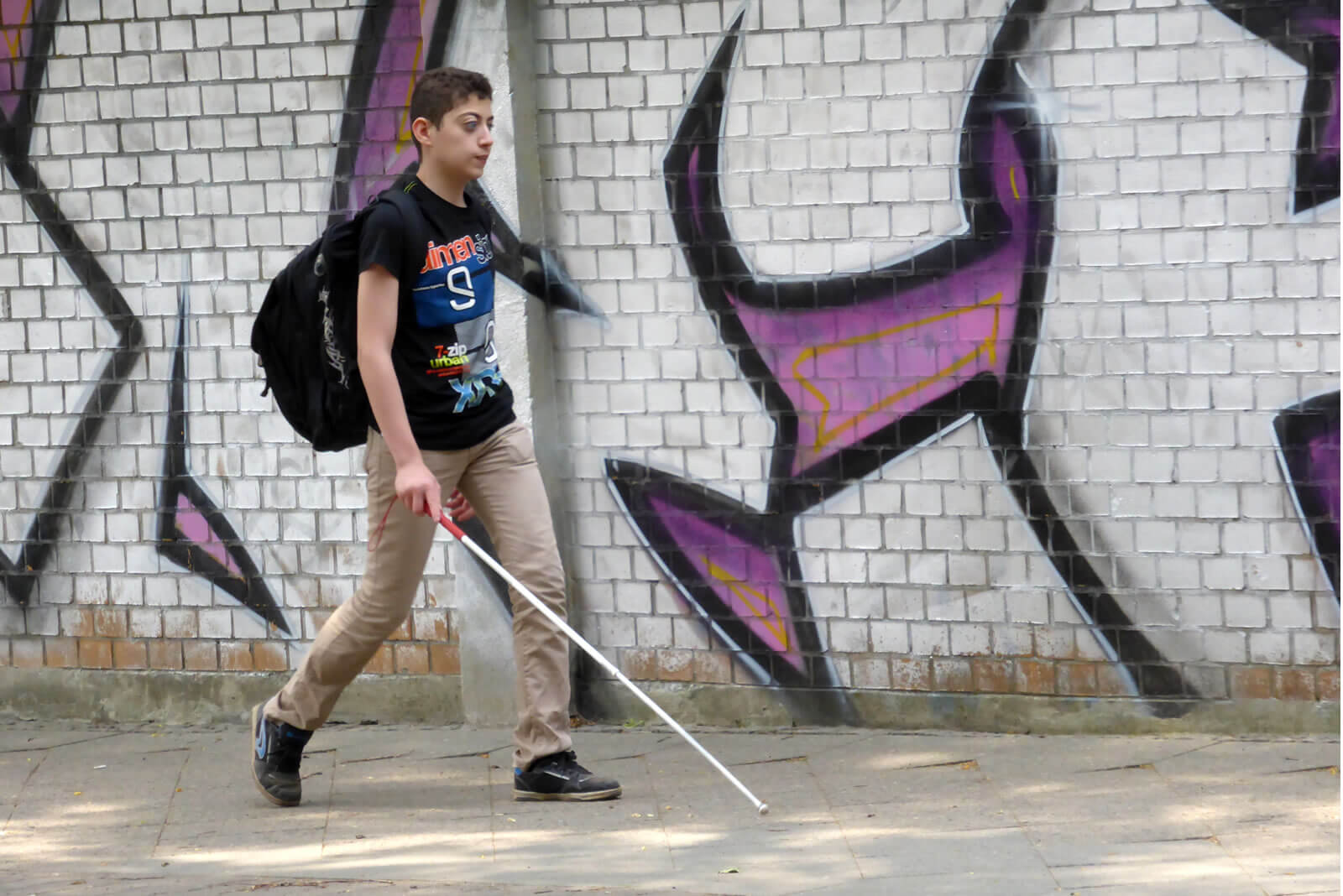 Junge mit Blindenstock überquert Zebrastreifen