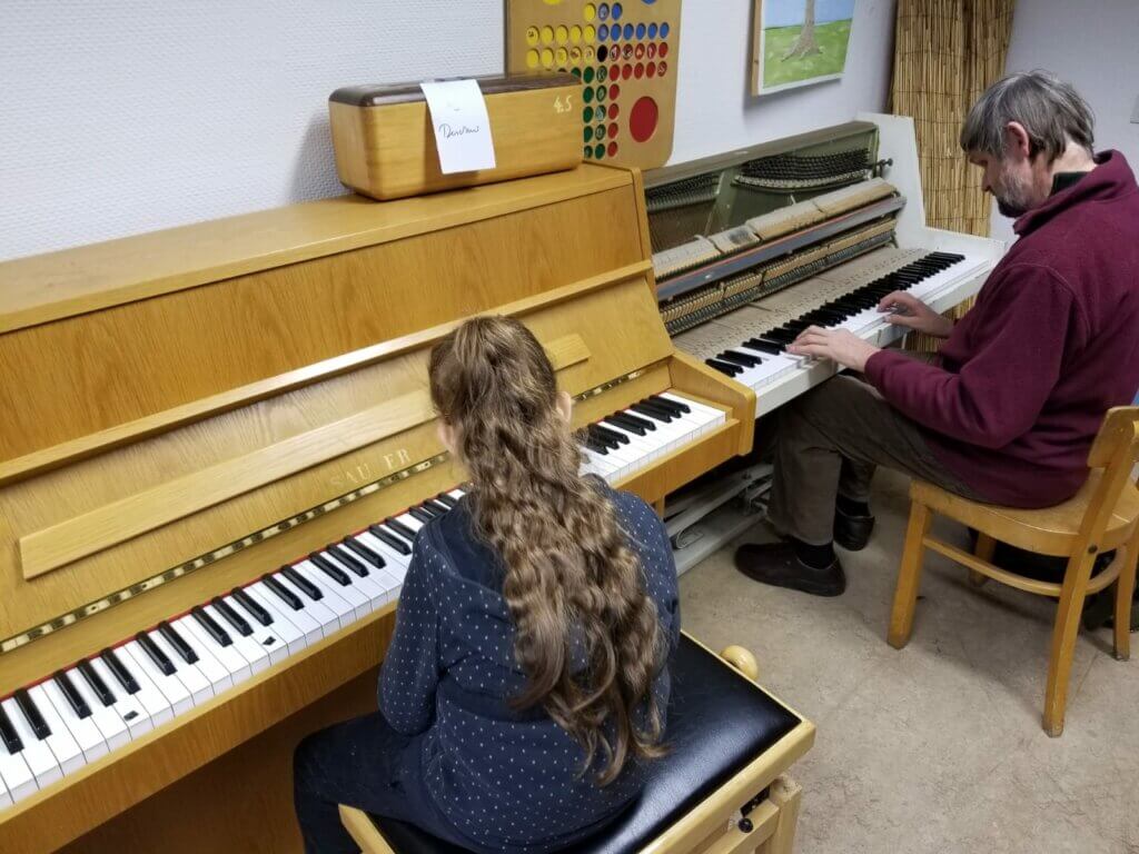 eine Schülerin übt am Klavier mit ihrem Klavierlehrer