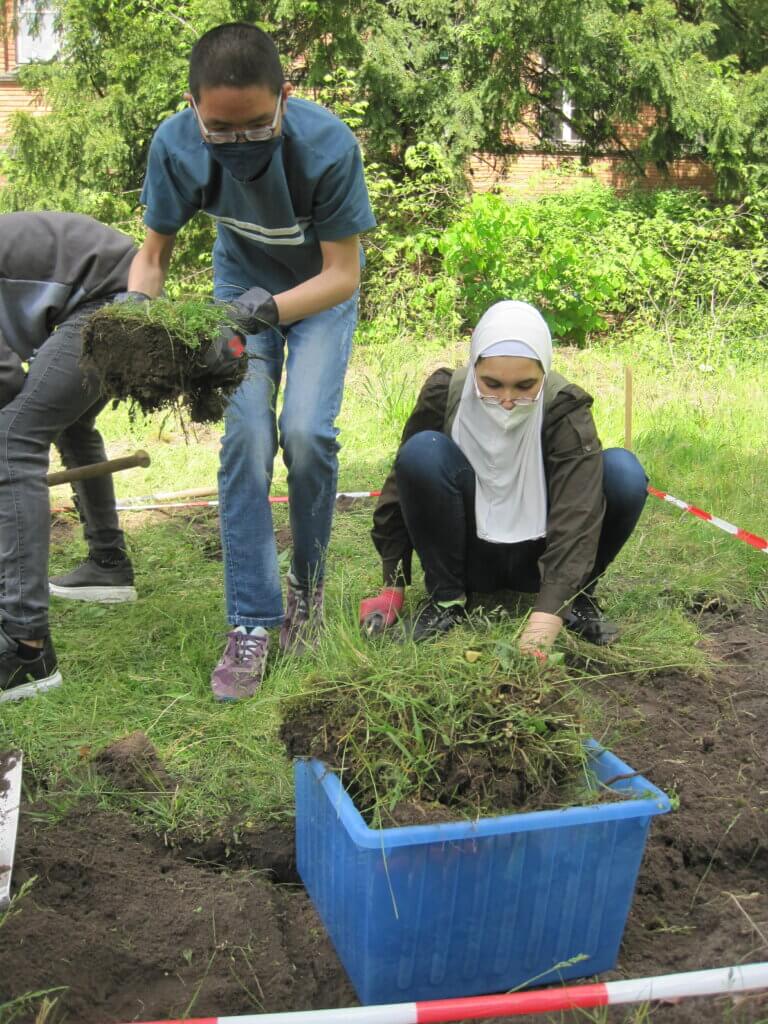 Schüler:innen entfernen Rasen für die Blumenwiese